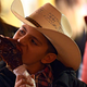 Teenager in cowboy hat eats turkey leg